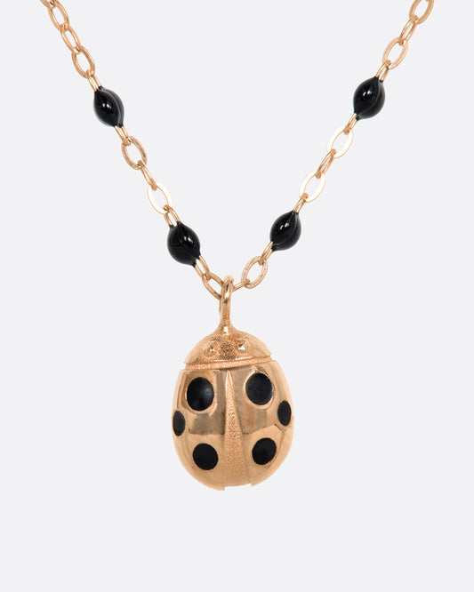 A classic rose gold gigi necklace with black resin beads and a rose gold ladybug pendant with black spots. View up close from the front.