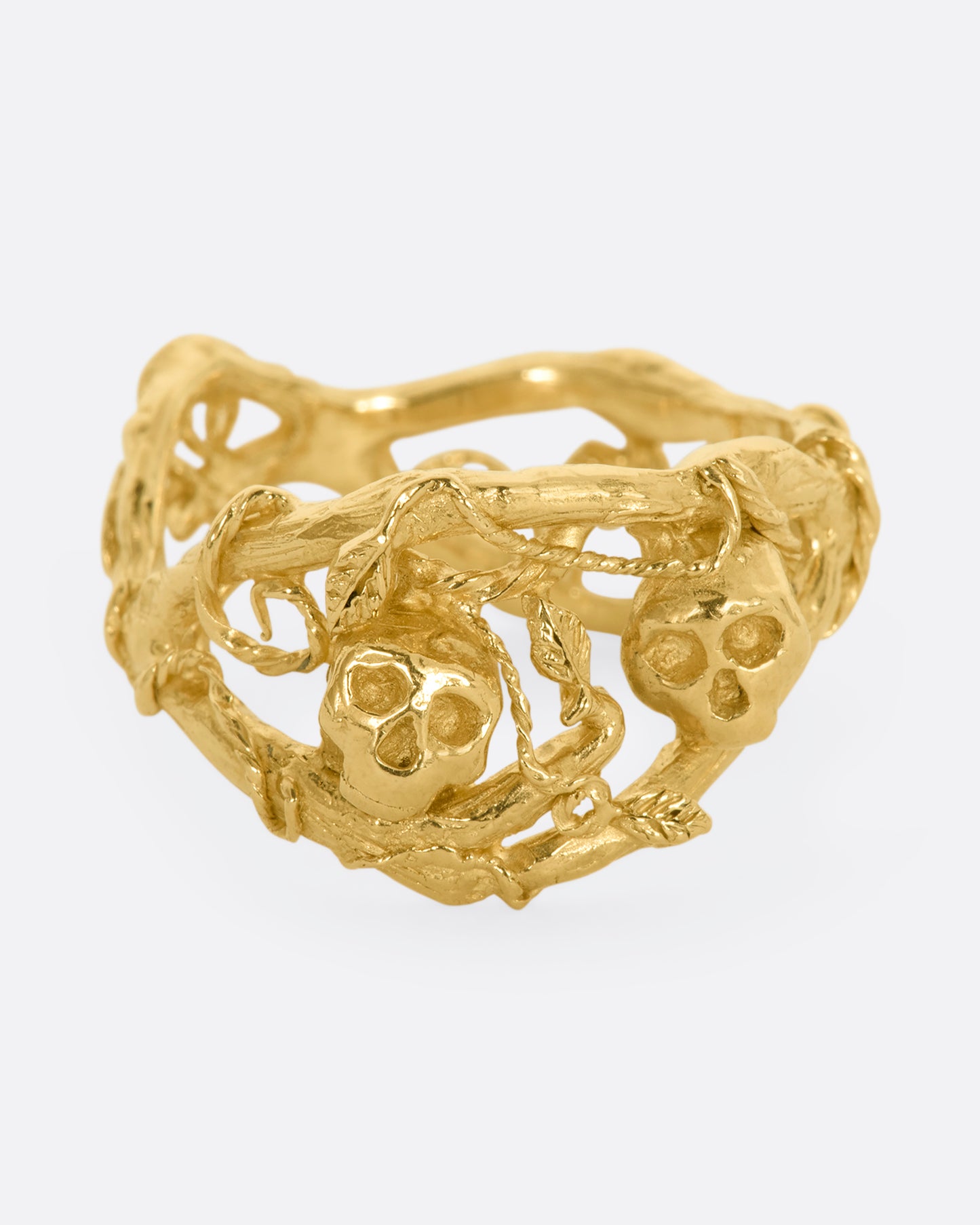 A yellow gold momento mori ring with organic branch and vine motif, featuring two skulls. View from the front.