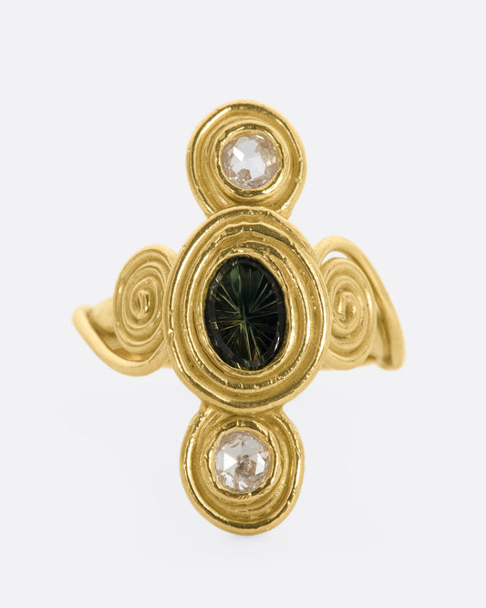 A yellow gold ring with circle and spiral motifs. At the center is a parti-color Australian sapphire with a rose cut diamond above and below. View from the front.