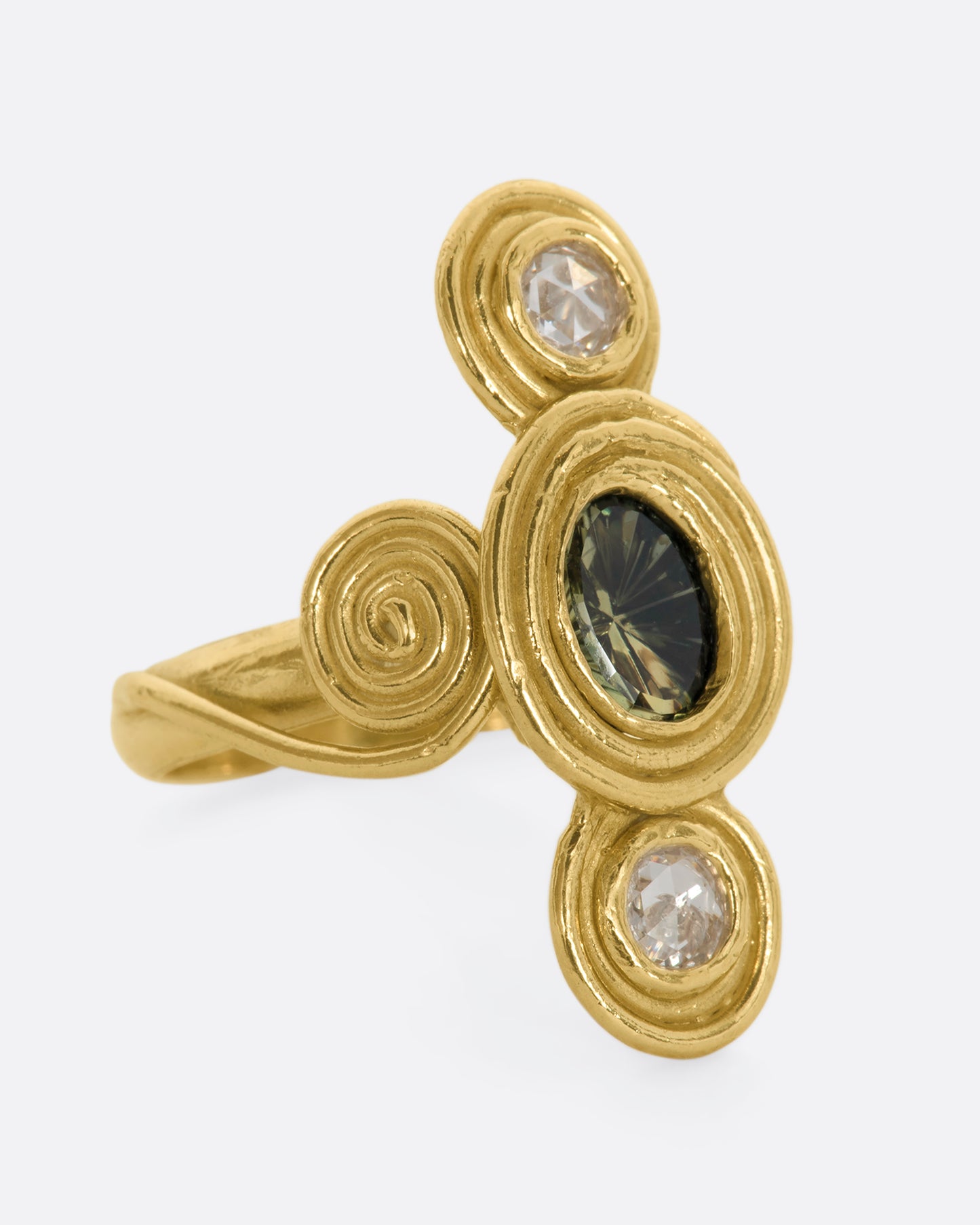 A yellow gold ring with circle and spiral motifs. At the center is a parti-color Australian sapphire with a rose cut diamond above and below. View from the alternate side.