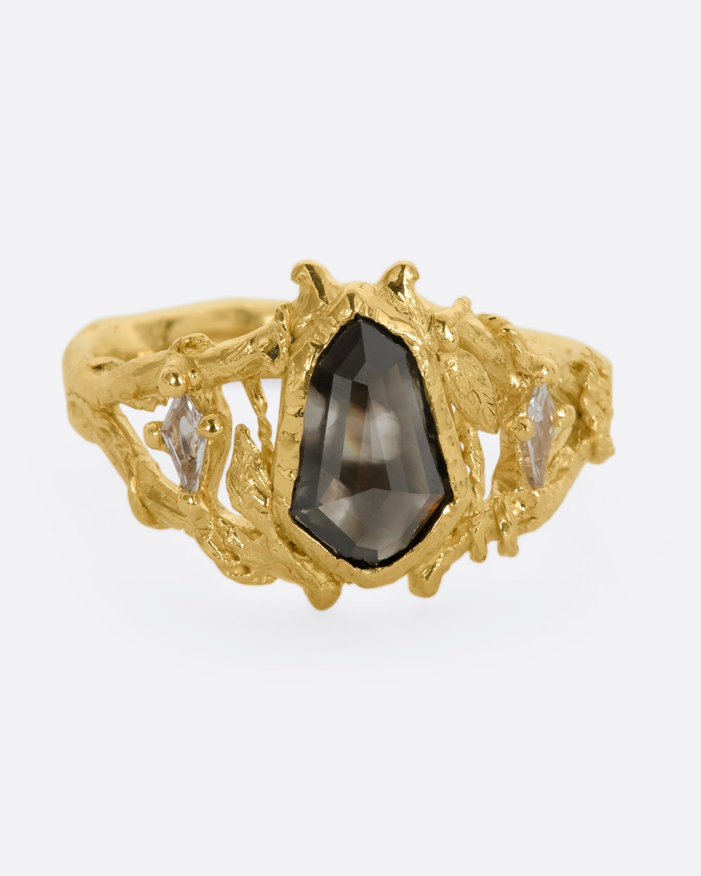 A yellow gold ring with an organic vine motif and a shield double cut black diamond at the center with white kite sapphires on either side. View from the front.