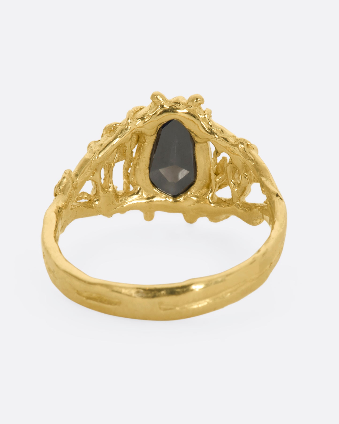 A yellow gold ring with an organic vine motif and a shield double cut black diamond at the center with white kite sapphires on either side. View from the back.