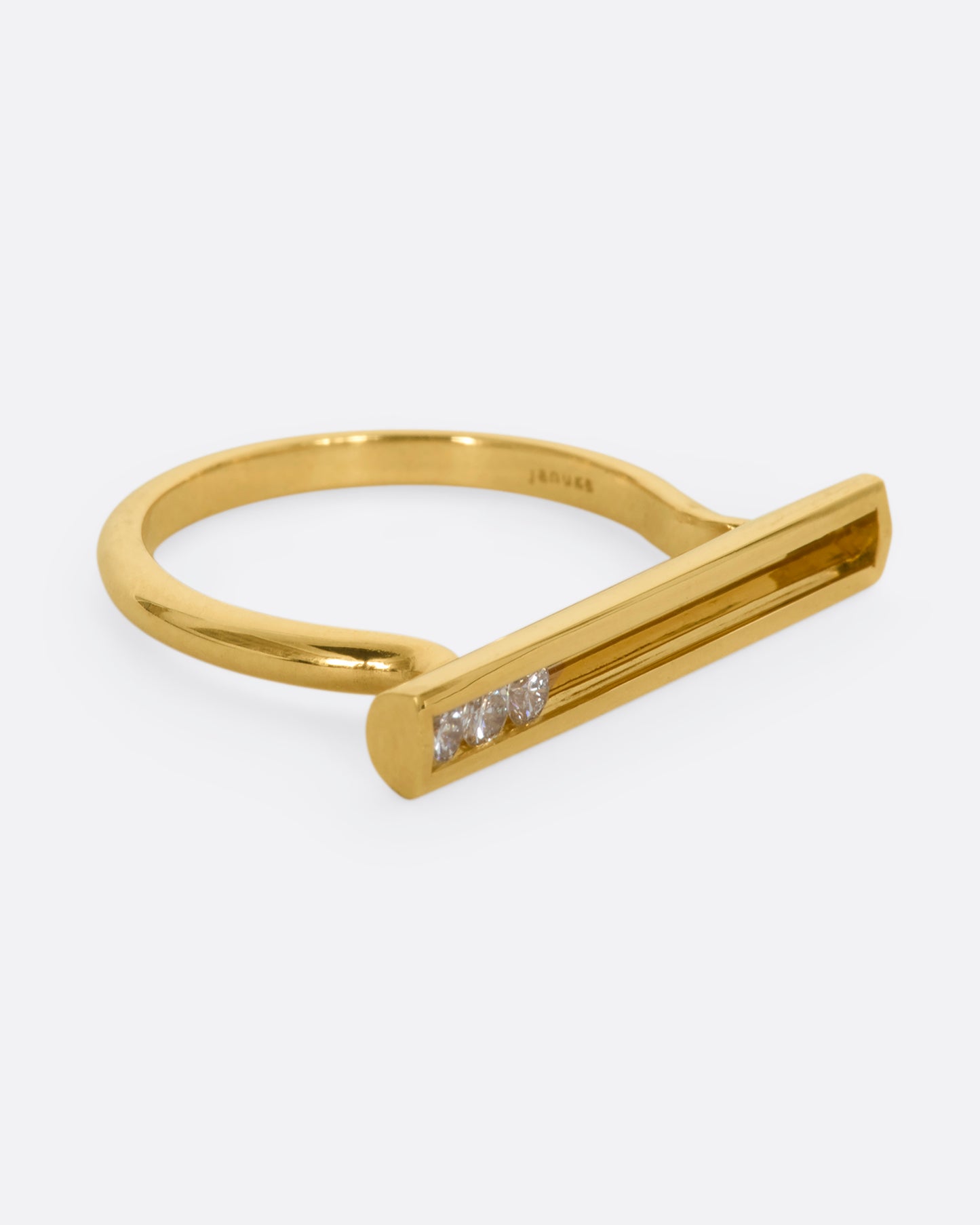 A polished yellow gold ring with a rectangular face that holds three channel set sliding diamonds. View from the alternate side.