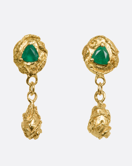 A pair of yellow gold drop earrings with vine motif and a trillion cut emerald on each. View from the front.