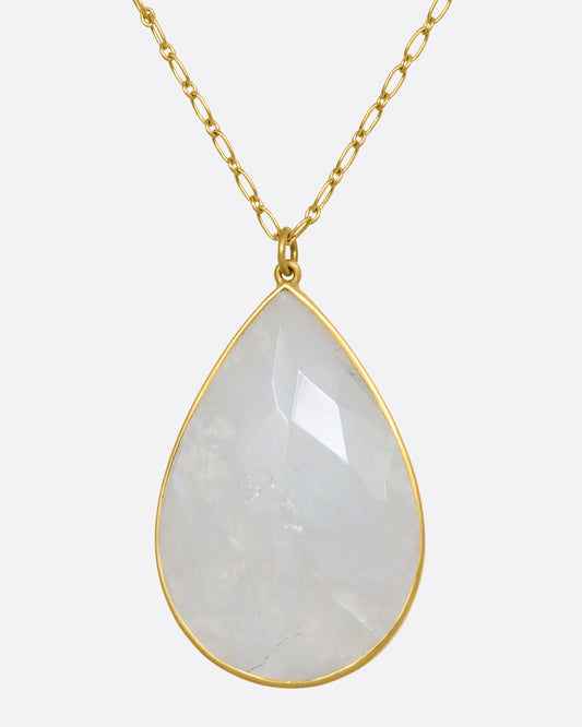 A tear drop shaped moonstone in a yellow gold bezel setting hanging from a yellow gold chain. View up close from the front.