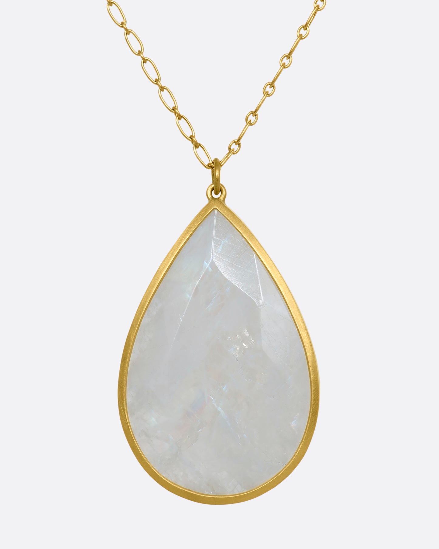 A tear drop shaped moonstone in a yellow gold bezel setting hanging from a yellow gold chain. View up close from the back