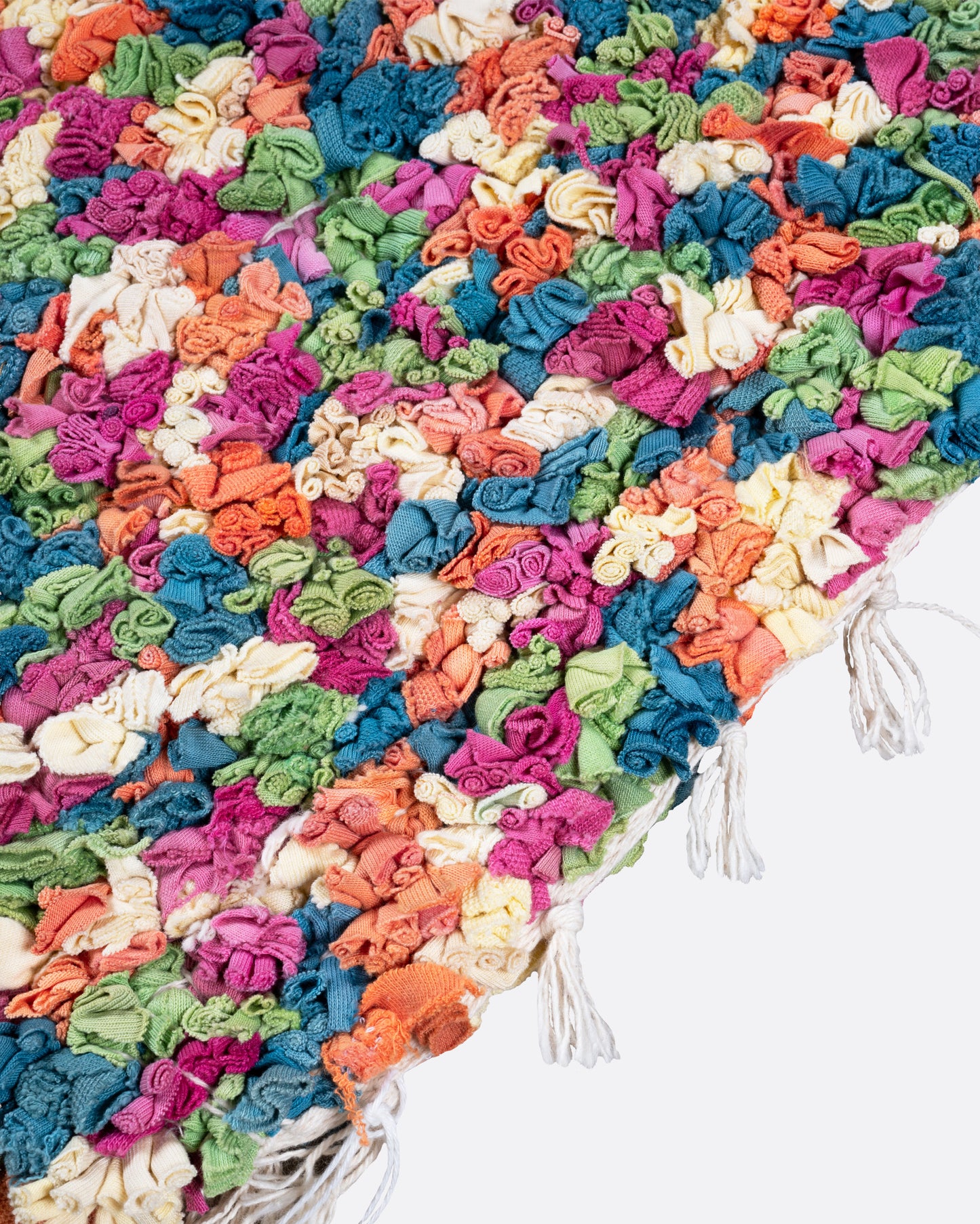 A close up of  green, red, orange, and white rectangular rag rug.