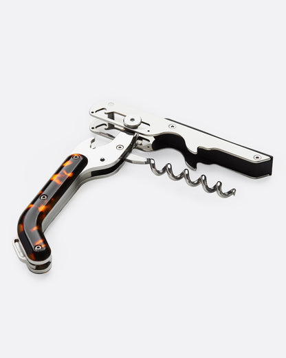 A wine key and bottle opener combo with a tortoiseshell handle and silver metal components, shown open on its side.