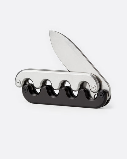 A stainless steel pocket knife with an interlocking mechanical hilt that moves with the blade and black handle, shown open from the side.