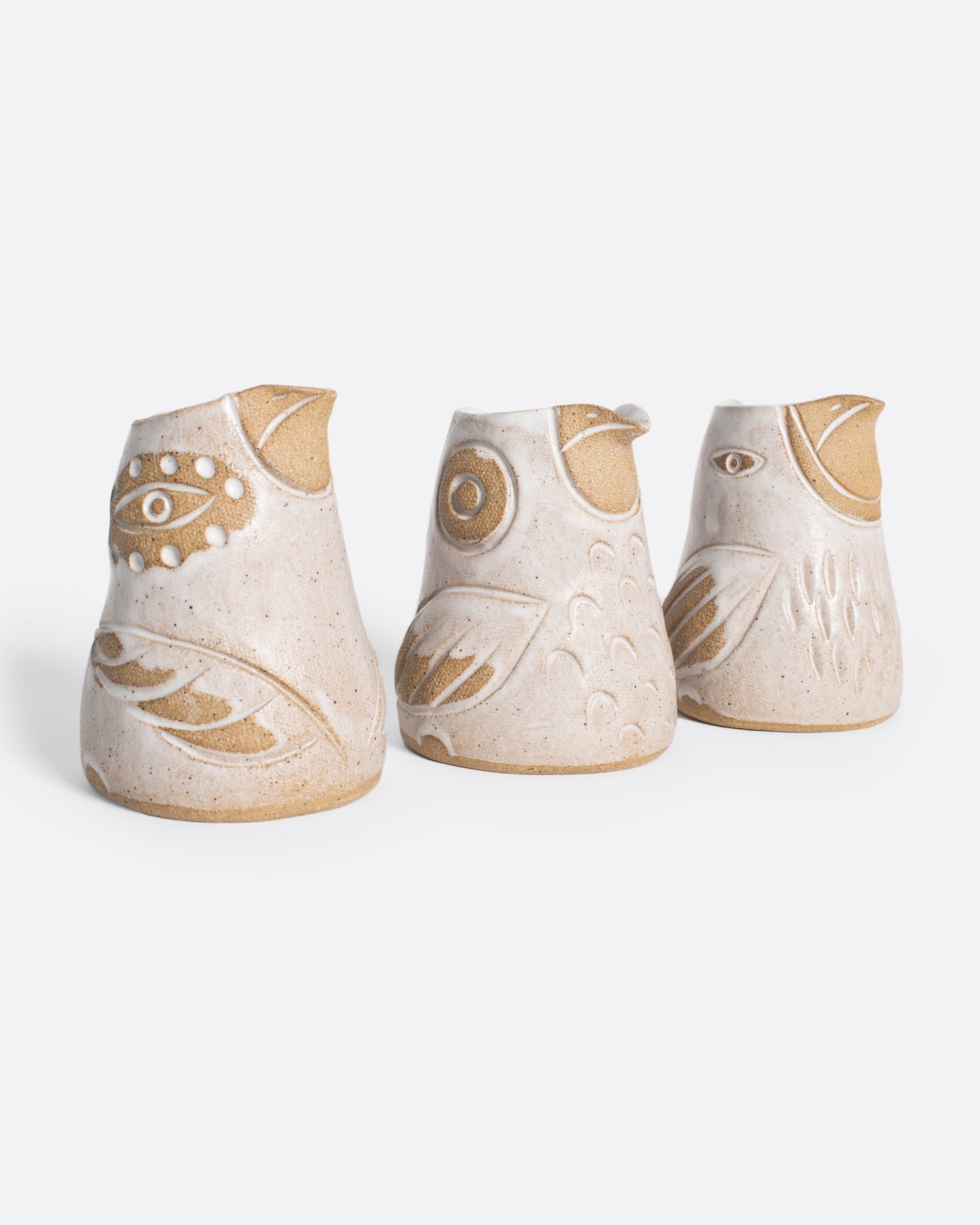 Angled line of three creamers shaped like birds in white and brown.