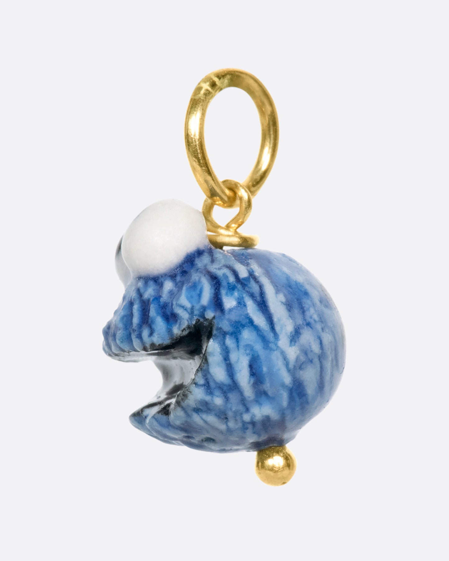 A porcelain Cookie Monster charm on a yellow gold bail.