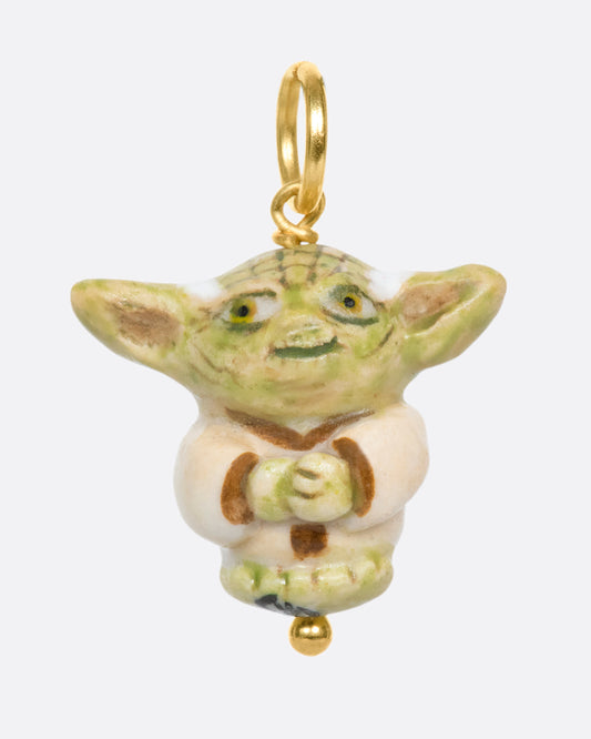 A handmade and painted porcelain Baby Yoda charm with a yellow gold bail.