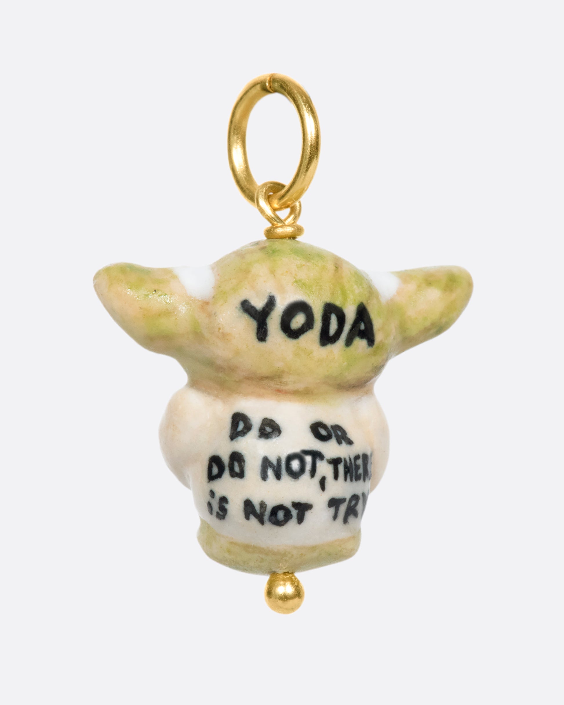 A handmade and painted porcelain Baby Yoda charm with a yellow gold bail.