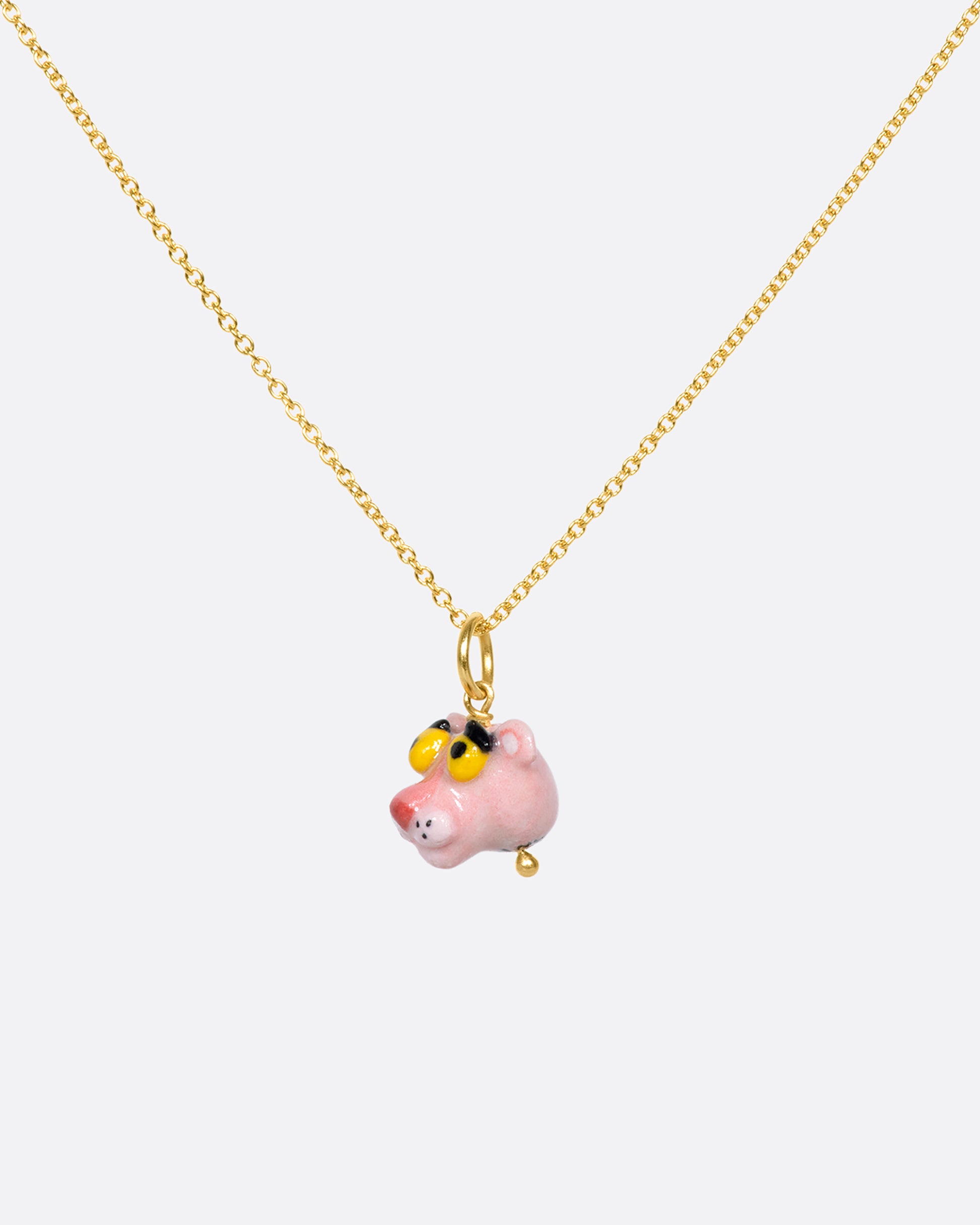 A handmade and painted porcelain Pink Panther charm with a 14k gold bail