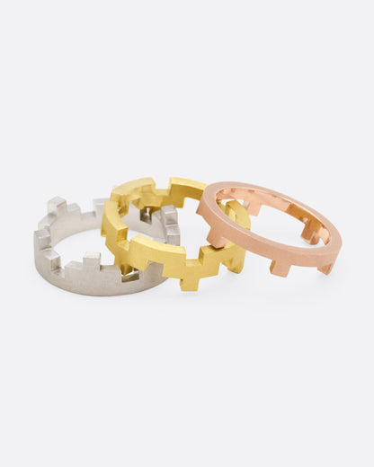 White, yellow and rose gold stacking rings, the three bands separated side by side
