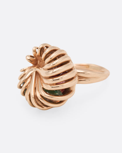 Rose gold swirl cage ring with emerald and tourmaline, angled view of the cage with the stones visible between the wires