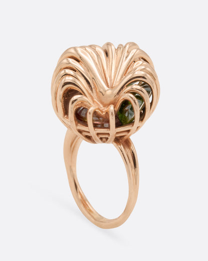 Rose gold swirl cage ring with emerald and tourmaline, front view of the wires curling over the top of the cage