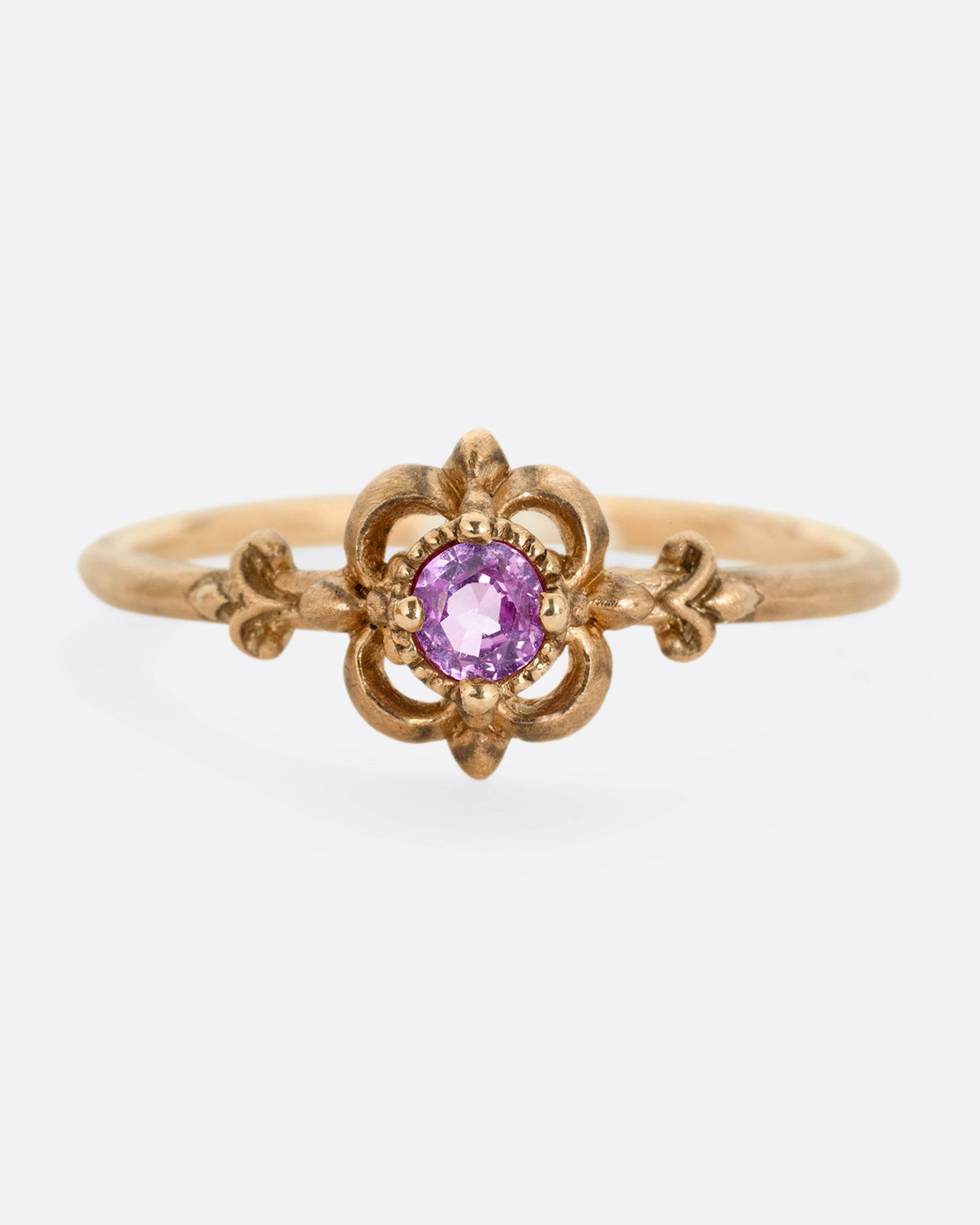 A yellow gold ring with a floral motif and pink tourmaline at the center. Shown from the front.
