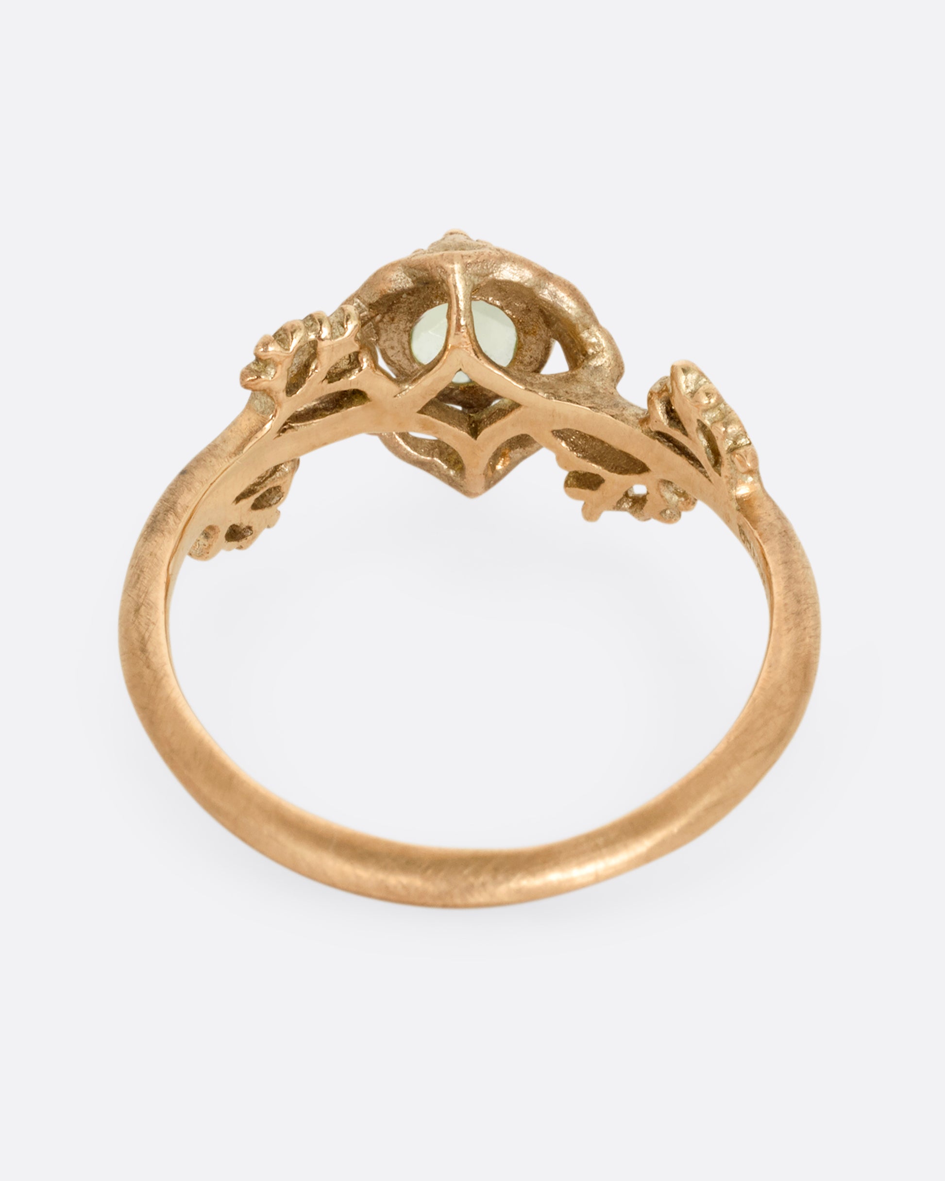 A yellow gold ring with a floral motif and peridot. Shown from the back.