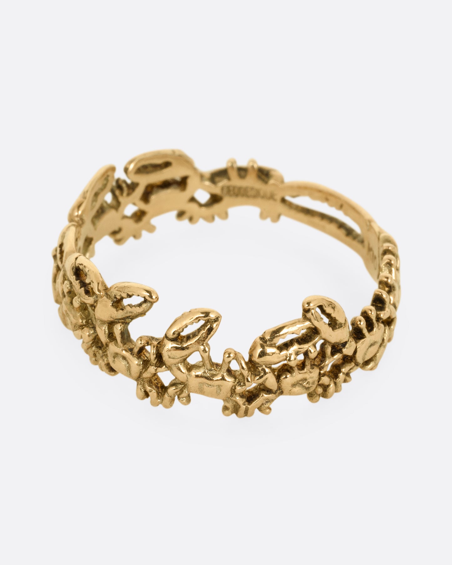 A yellow gold ring with a queue of crabs. Shown from the side.