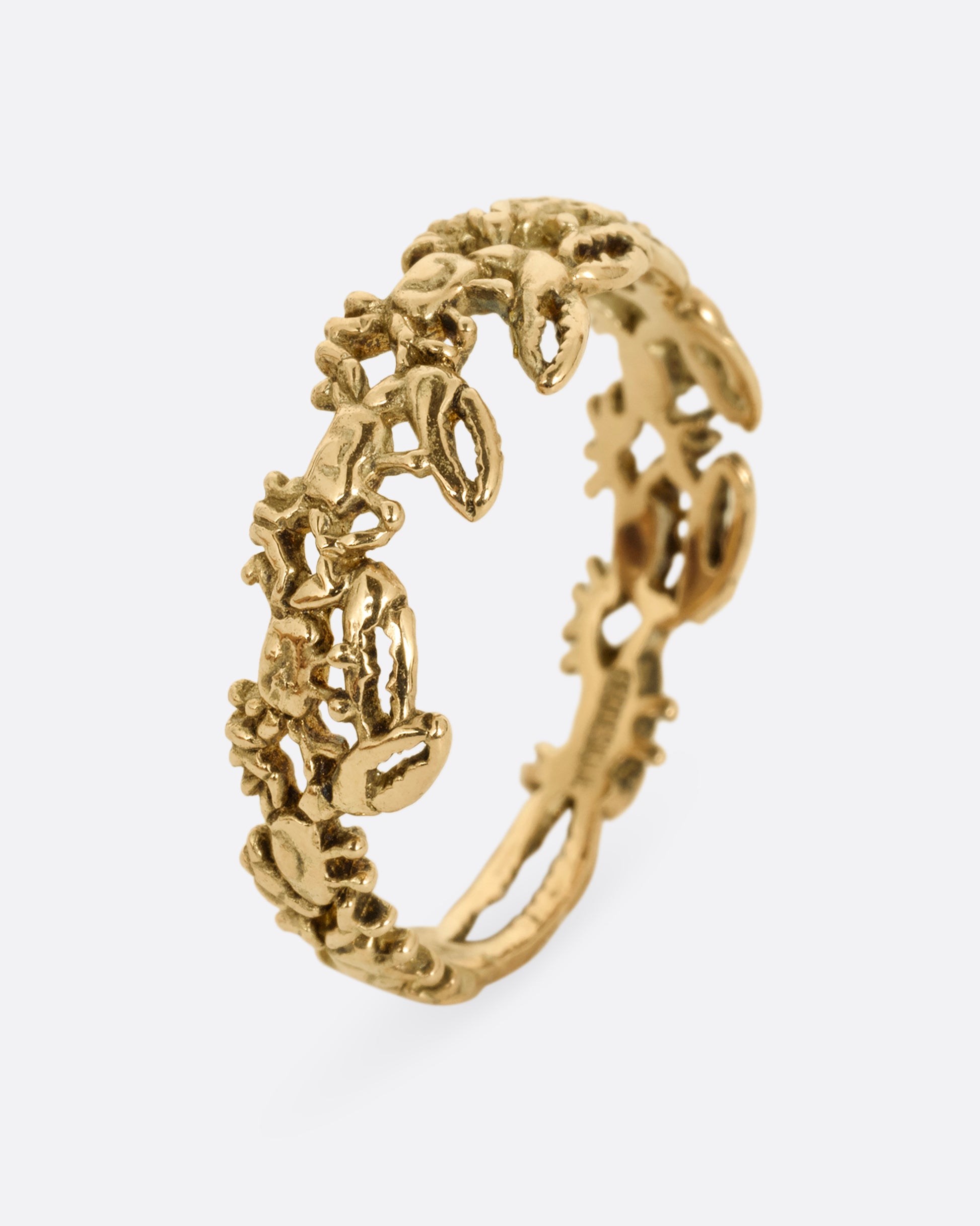 A yellow gold ring with a queue of crabs. Shown standing up from the side.