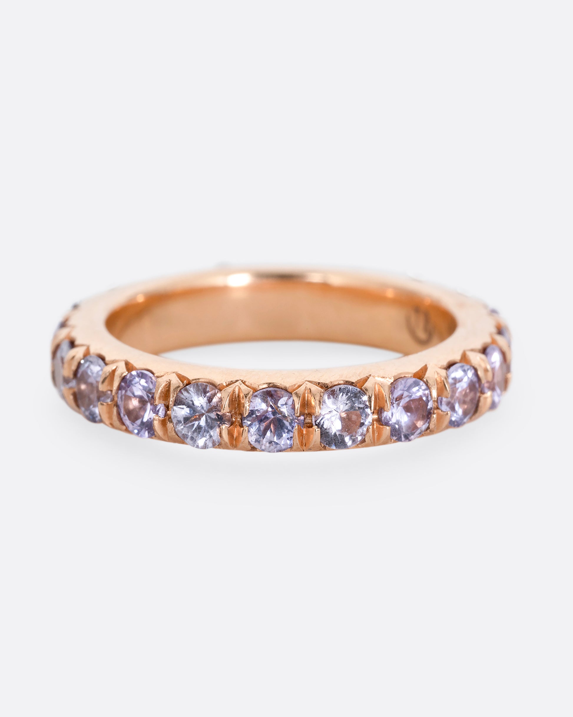 A rose gold eternity ring with lavender sapphires. Shown from the front.