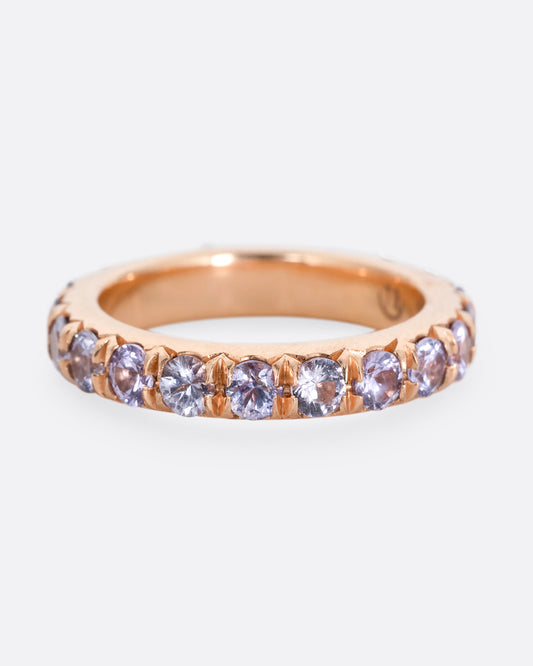 A rose gold eternity ring with lavender sapphires. Shown from the front.