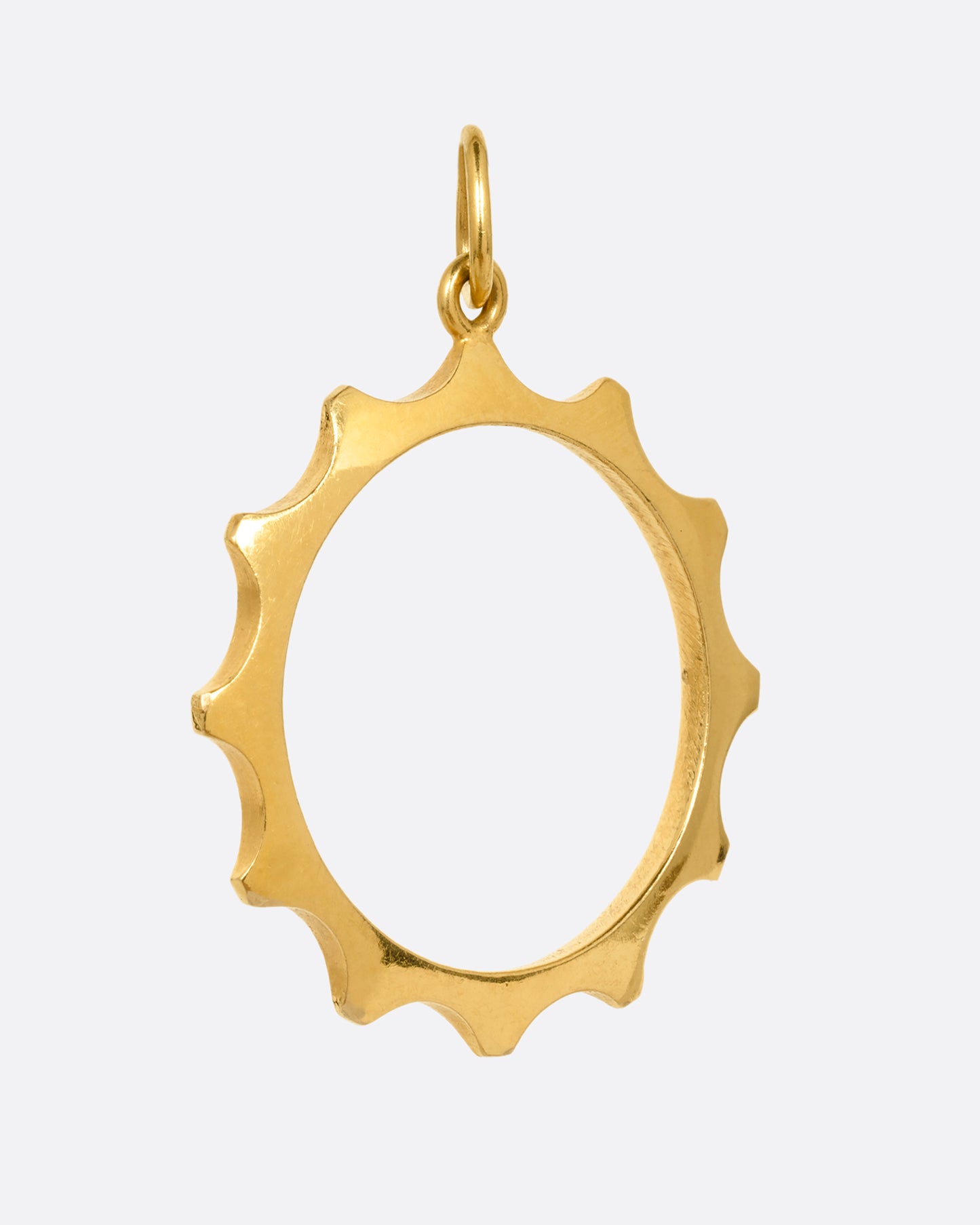 A yellow gold sun charm with an open center shown from the side.
