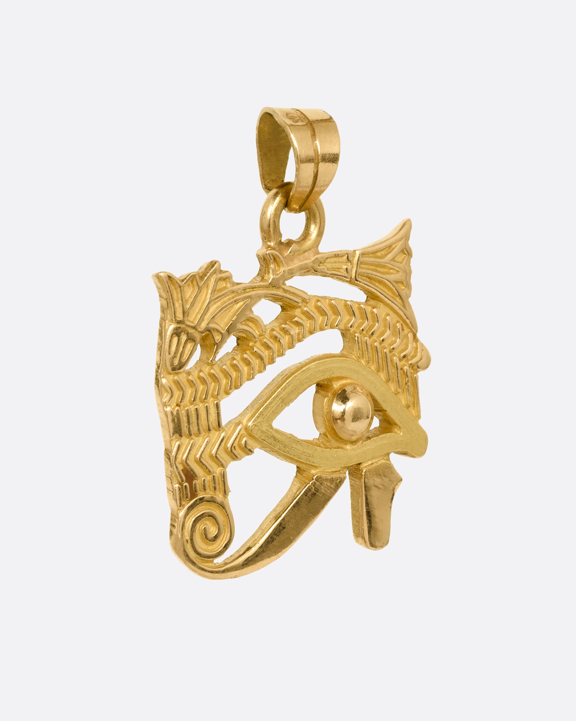 A yellow gold Eye of Horus pendant shown from the side.