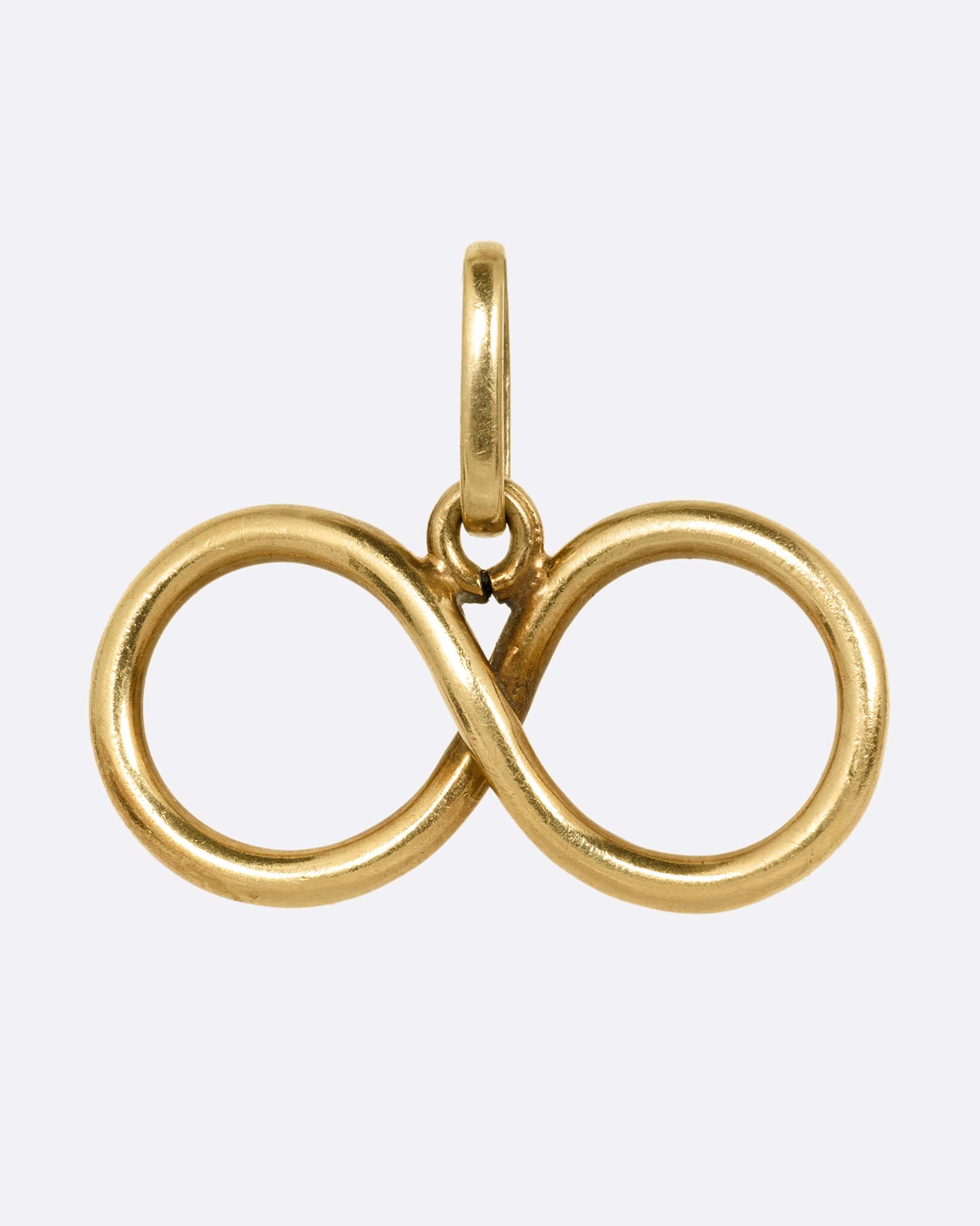 A yellow gold infinity pendant shown from the front.