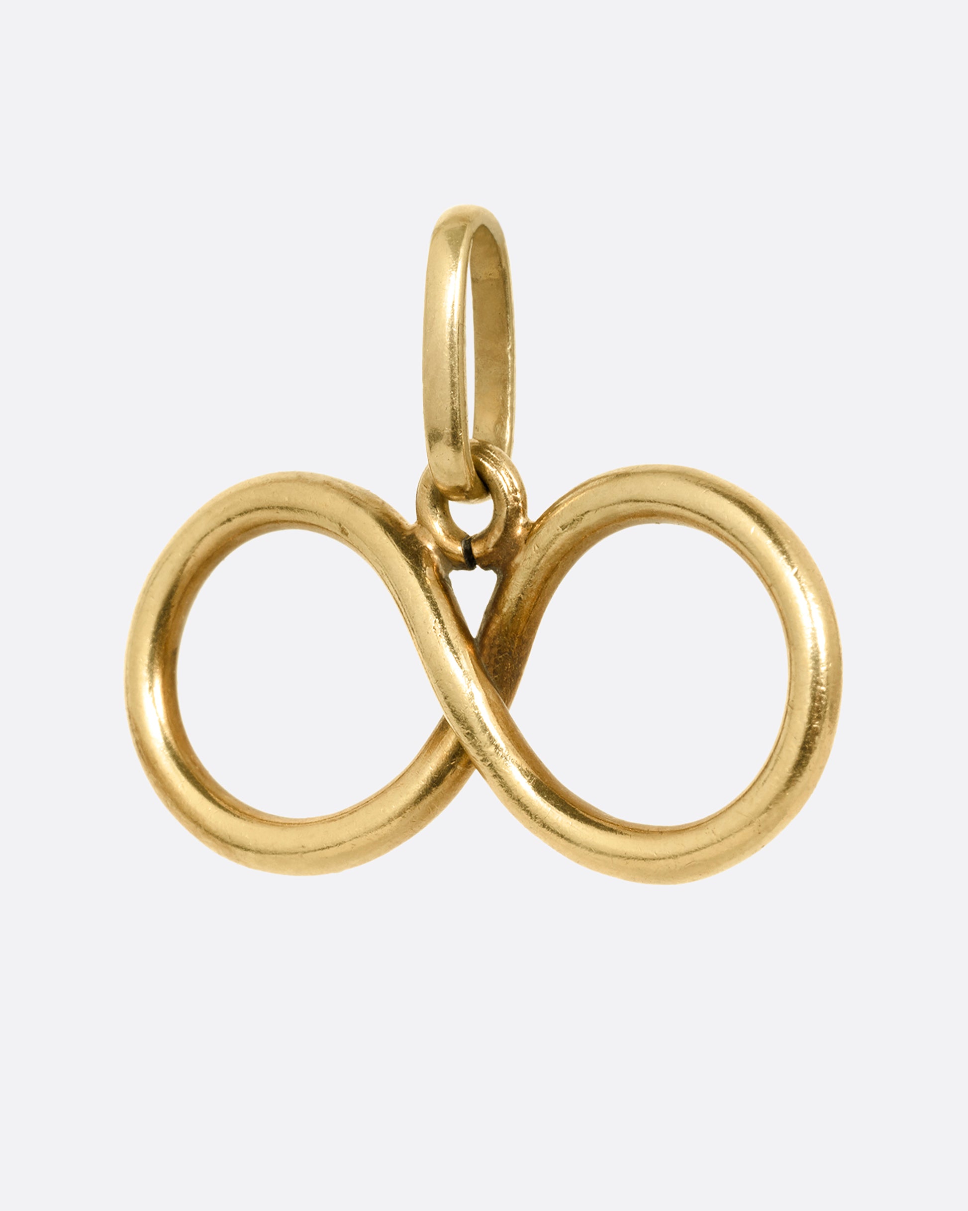 A yellow gold infinity pendant shown from the side.