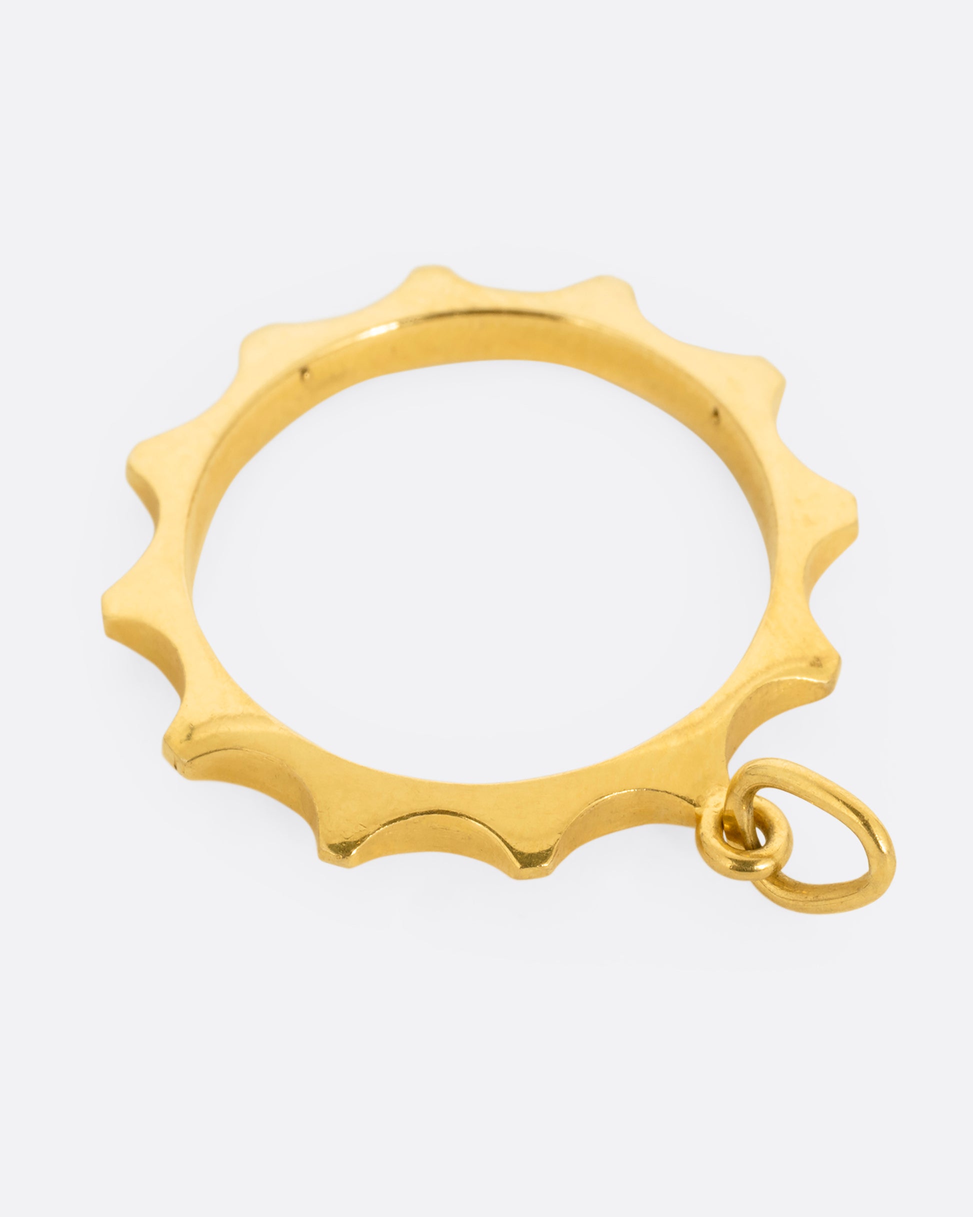 A yellow gold sun charm with an open center shown from the back.