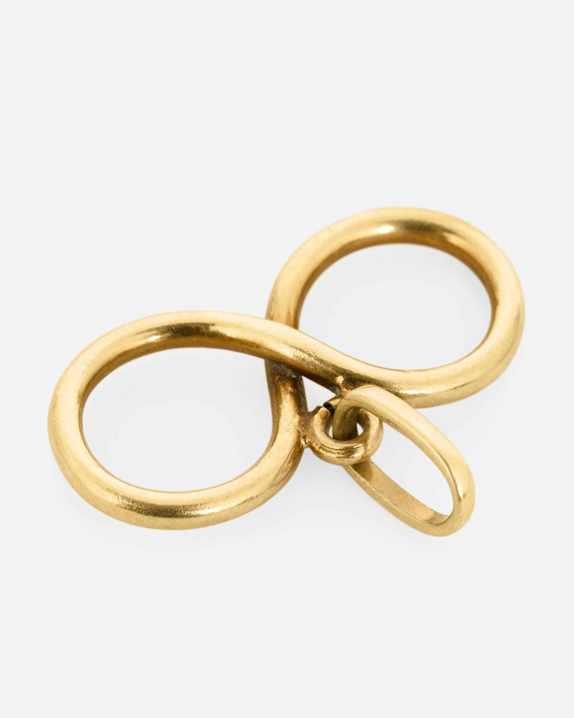 A yellow gold infinity pendant shown lying flat from the top.