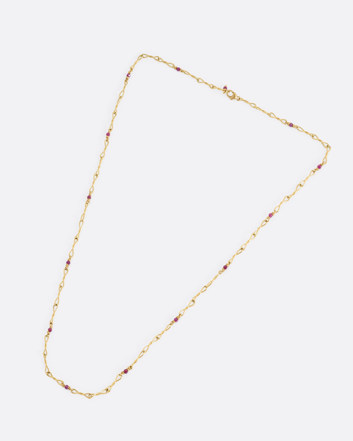 A yellow gold necklace with twisted links and ruby beads. Shown from the front.