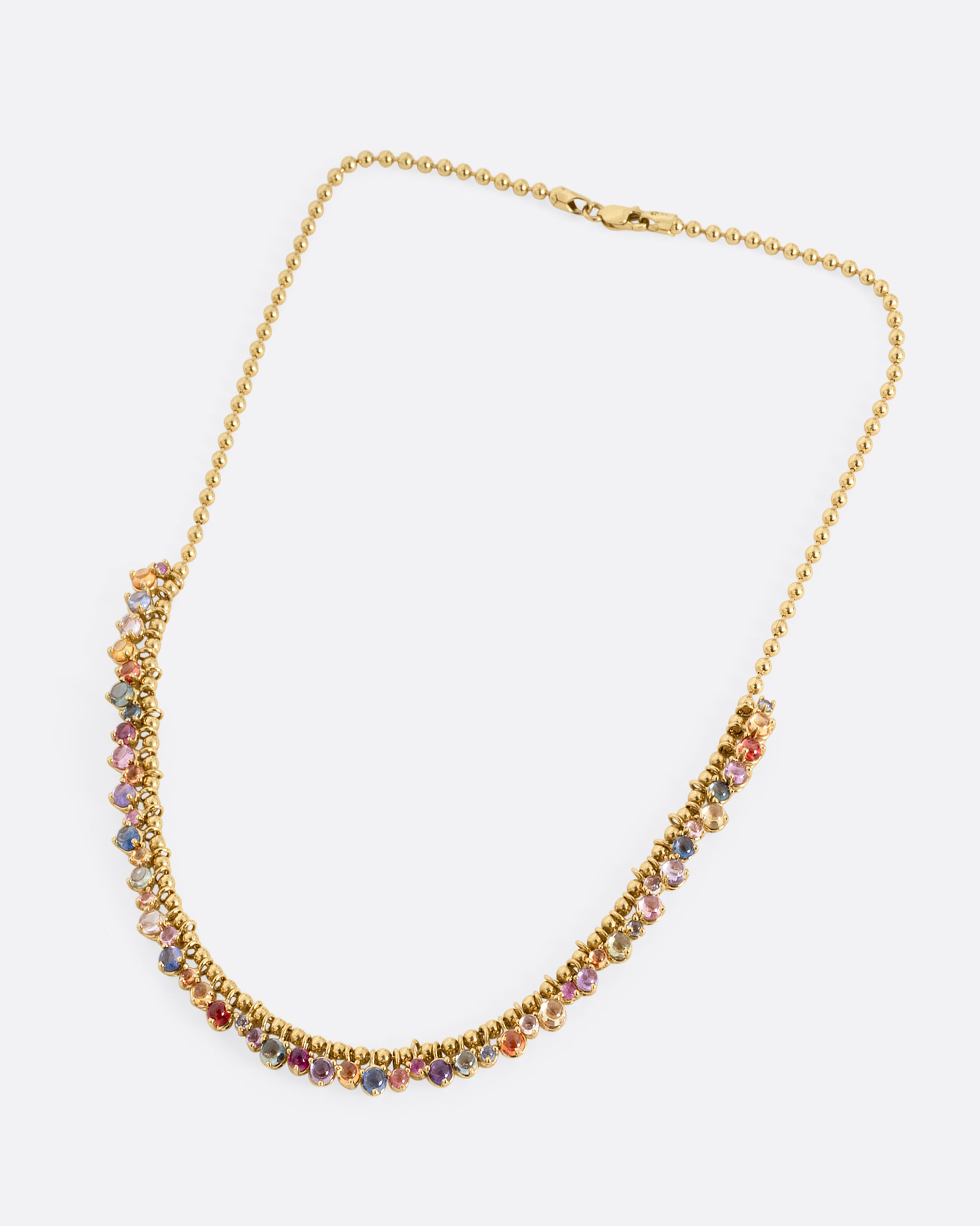 A yellow gold ball chain necklace with many multicolored sapphire dangles. Shown from the front.