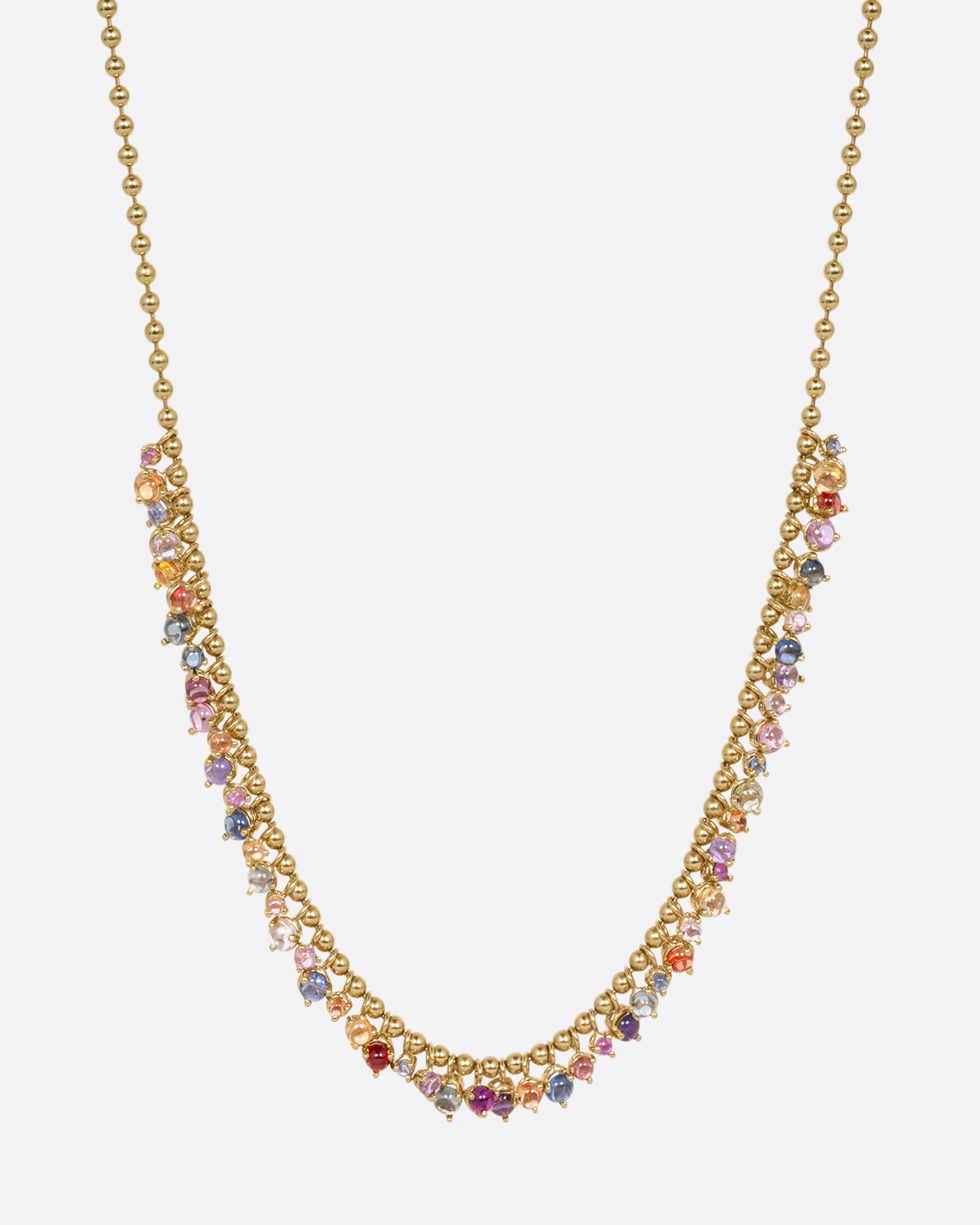 A yellow gold ball chain necklace with many multicolored sapphire dangles. Shown from the front.
