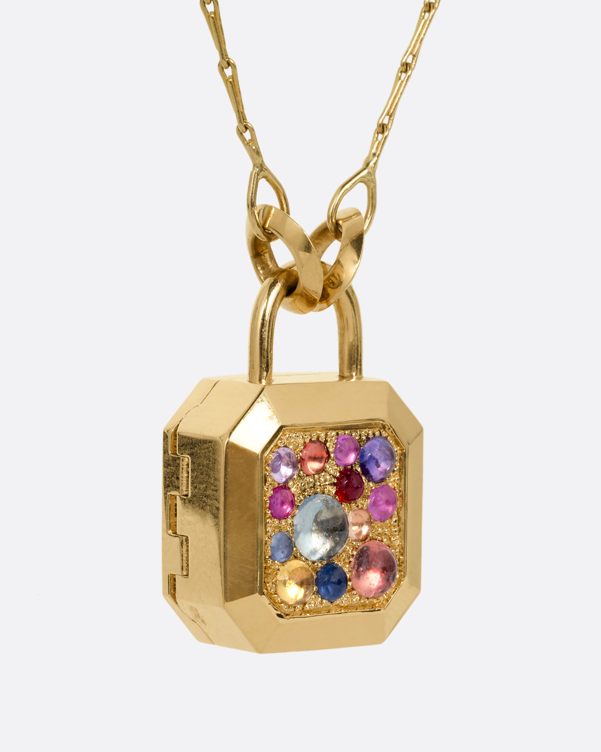 A yellow gold necklace with a padlock shaped locket pendant with multicolored sapphire on its face. Shown from the side.