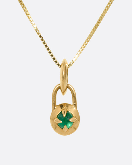 A yellow gold box chain necklace with a prong set emerald cabochon. Shown from the front.