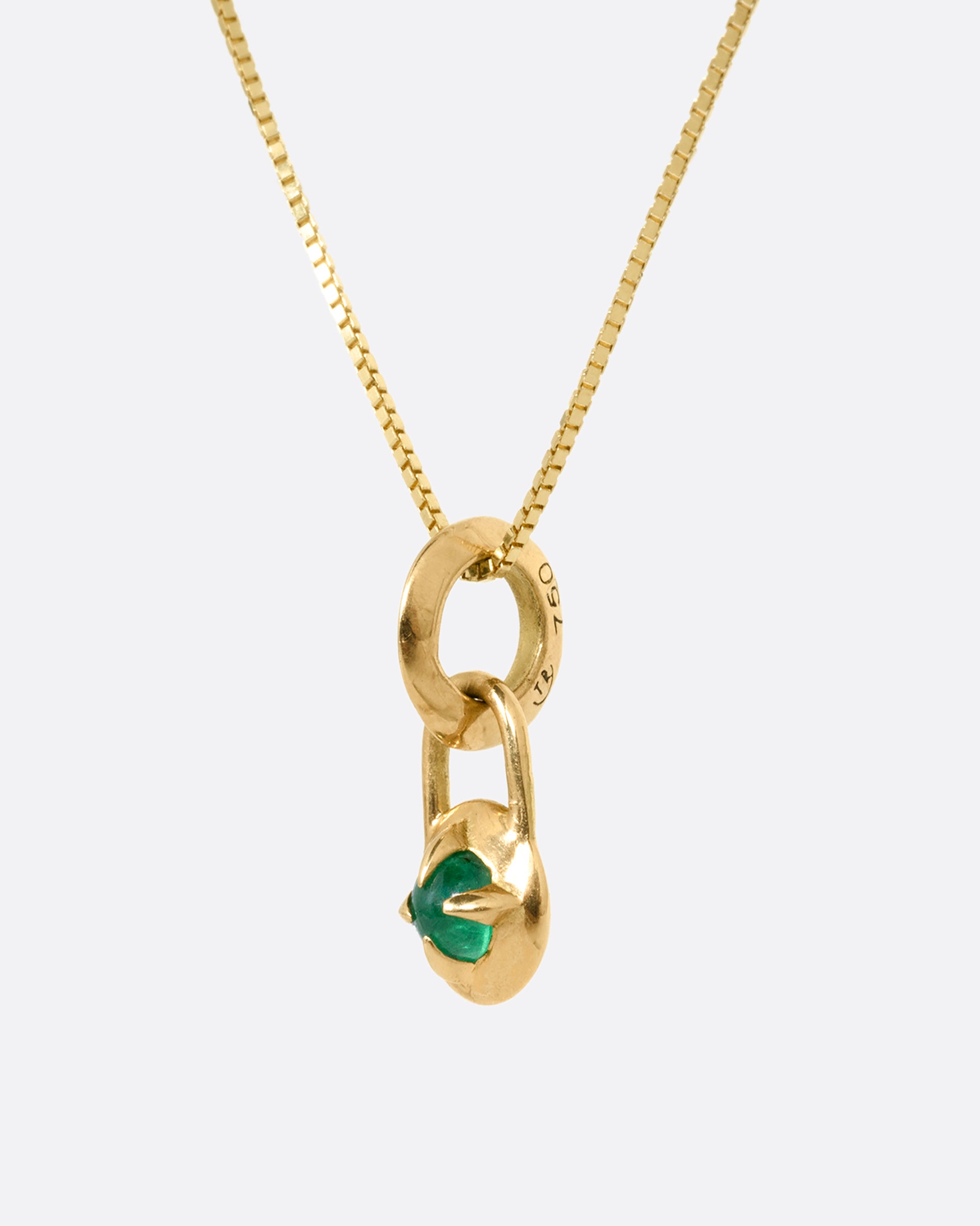 A yellow gold box chain necklace with a prong set emerald cabochon. Shown from the side.