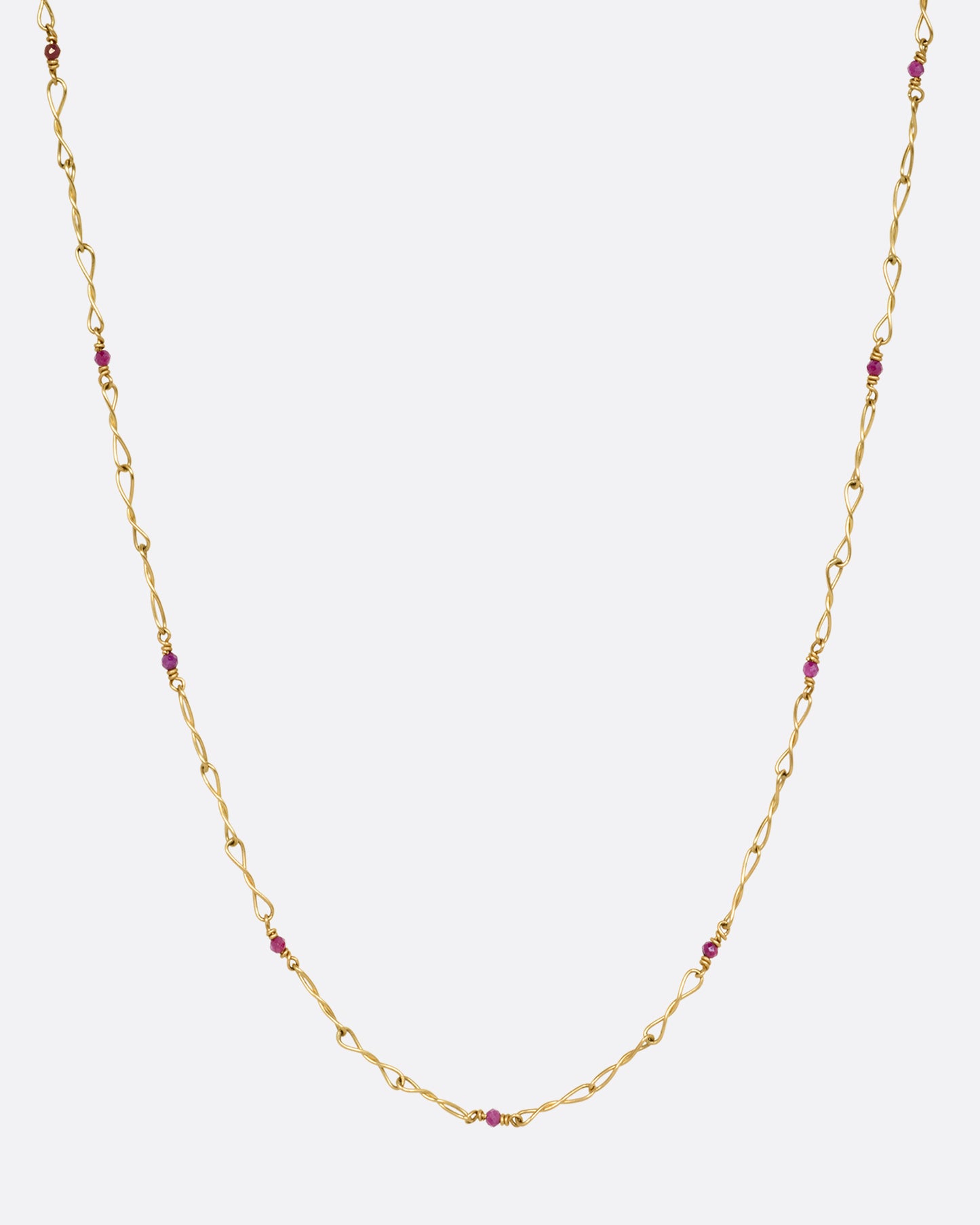 A yellow gold necklace with twisted links and ruby beads. Shown from the front.