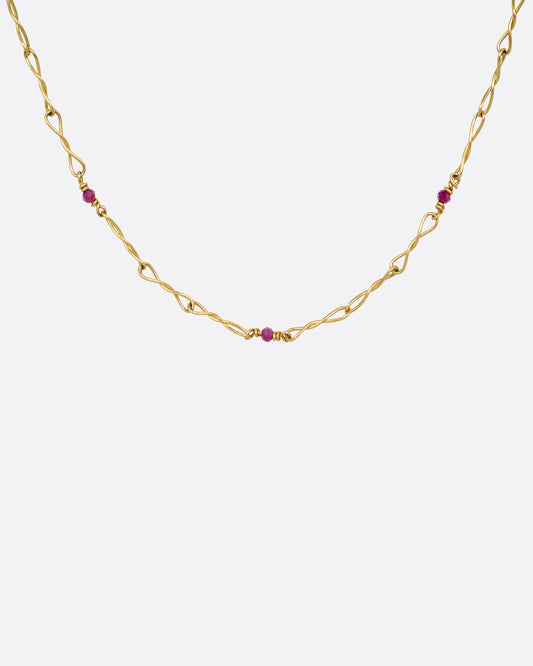 A yellow gold necklace with twisted links and ruby beads. Shown from the front.