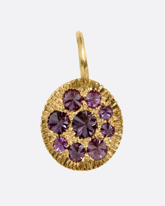 A yellow gold medallion with reverse set lavender diamonds, shown from the front.