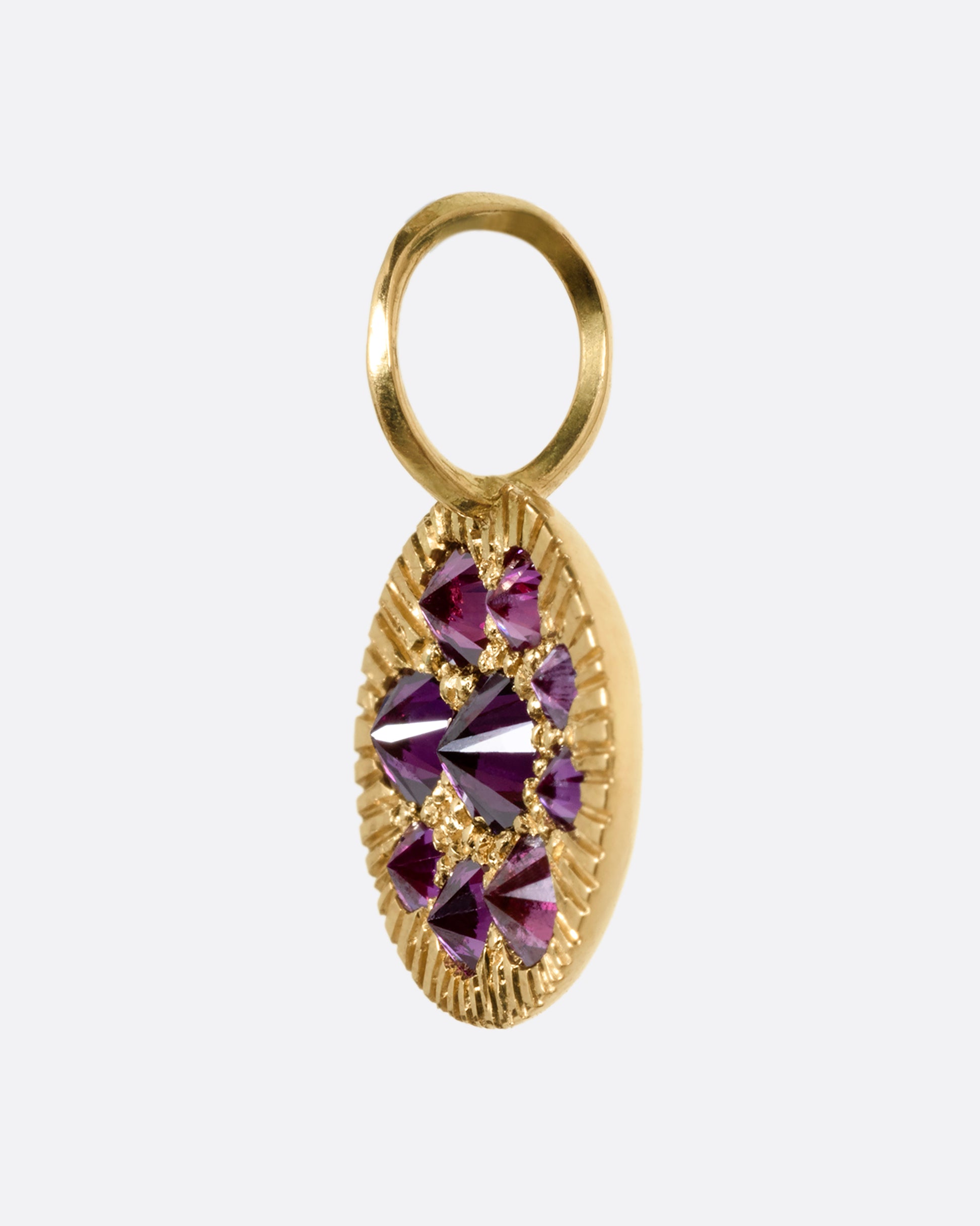 A yellow gold medallion with reverse set lavender diamonds, shown from the side.