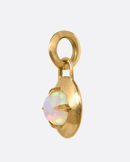 A round yellow gold pendant with a prong set opal, shown from the side.