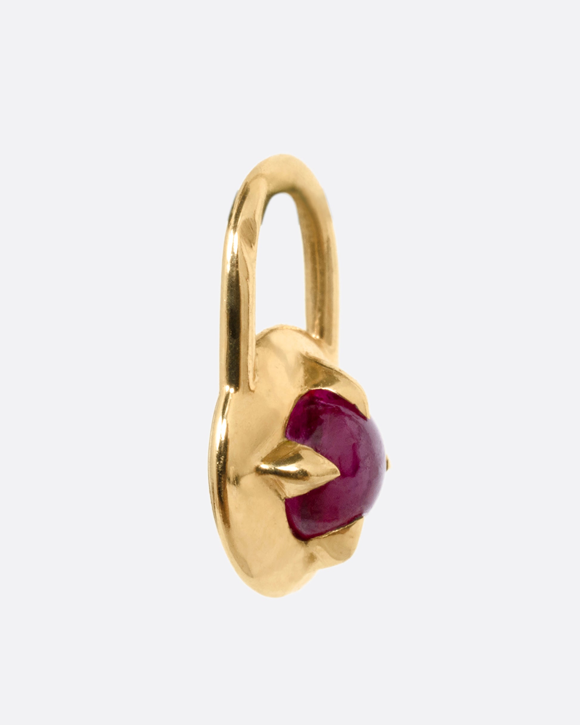 A yellow gold padlock shaped pendant with a prong set ruby cabochon. Shown from the side.