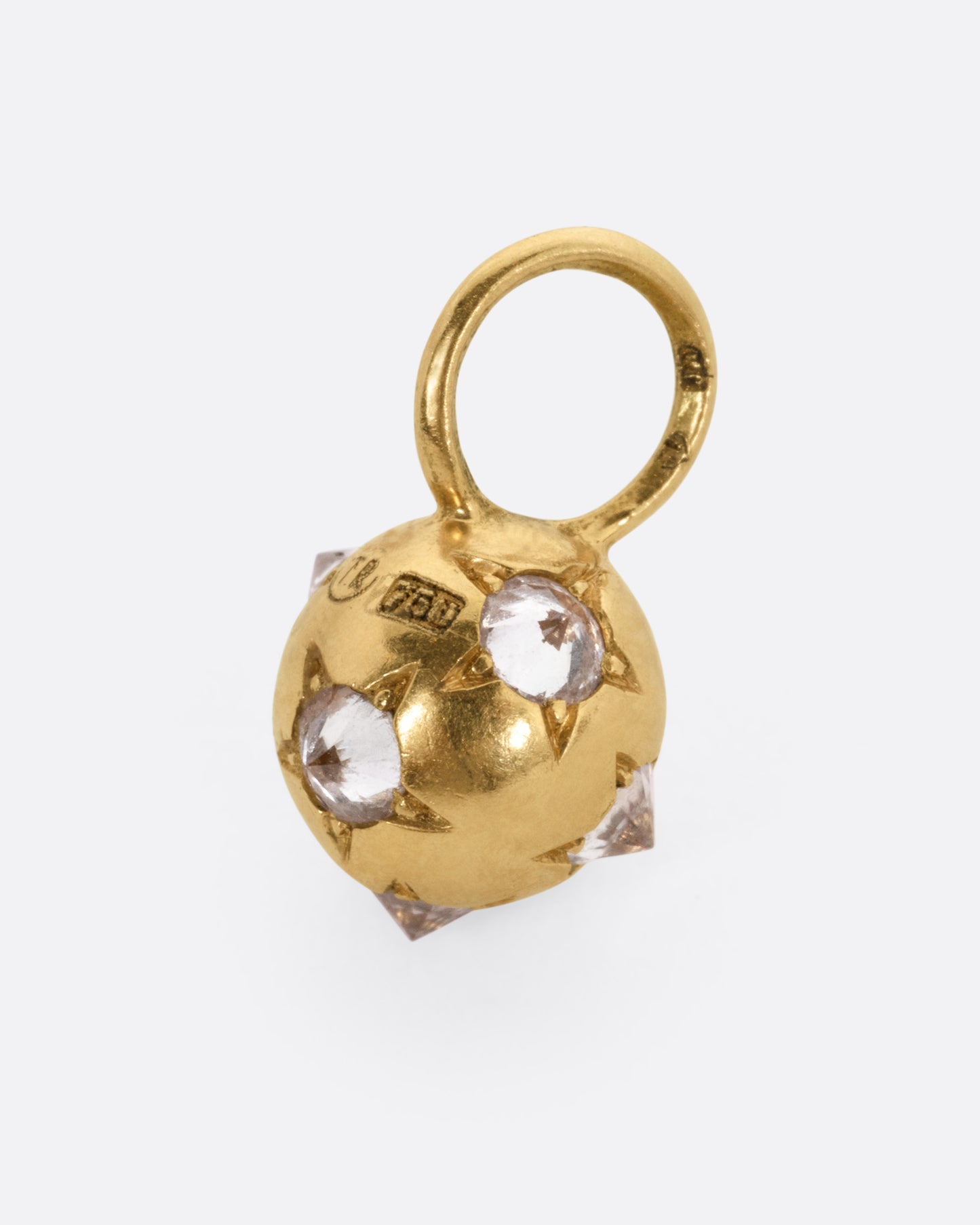 A yellow gold orb shaped charm with reverse set diamonds, shown from the side.