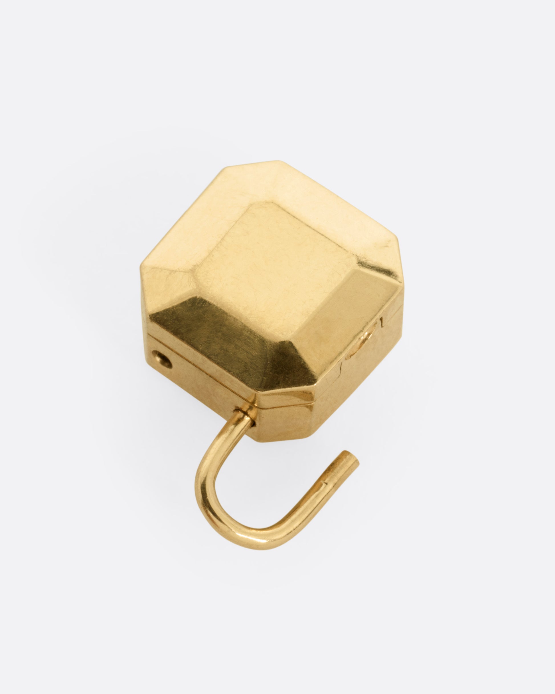 A yellow gold padlocket pendant featuring a large, faceted green emerald, shown from the back open.