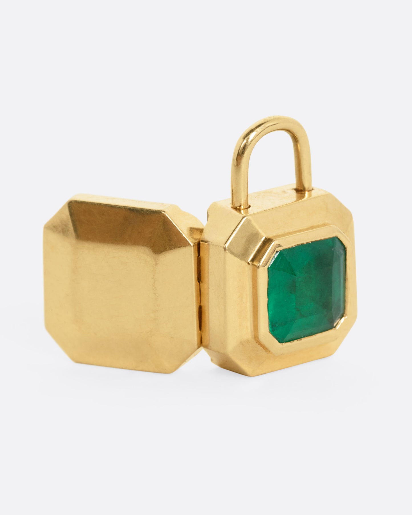 A yellow gold padlocket pendant featuring a large, faceted green emerald, shown from the back open.