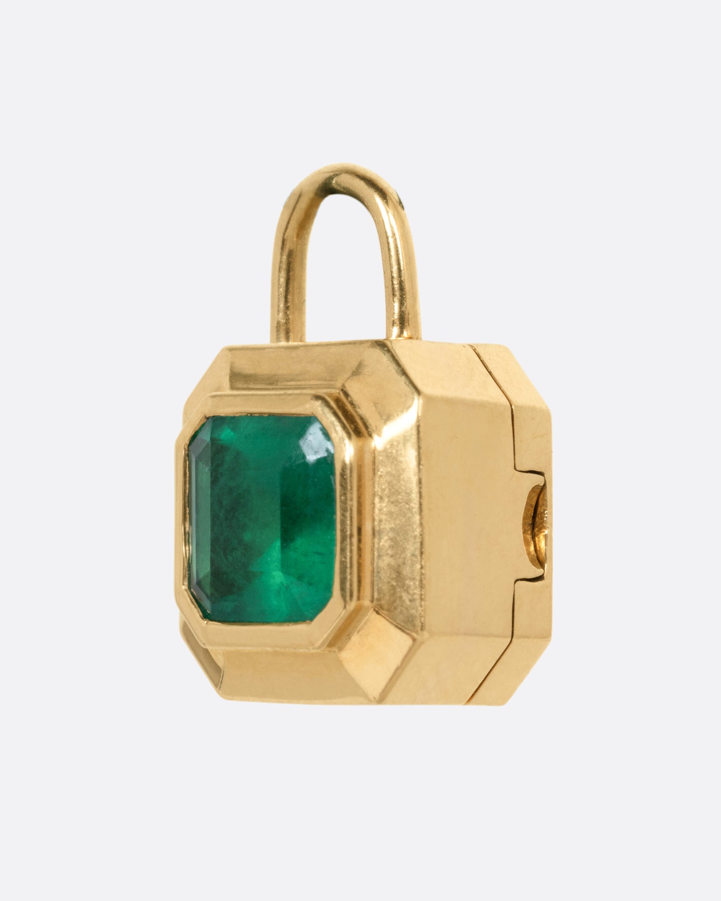 A yellow gold padlocket pendant featuring a large, faceted green emerald, shown from the side.
