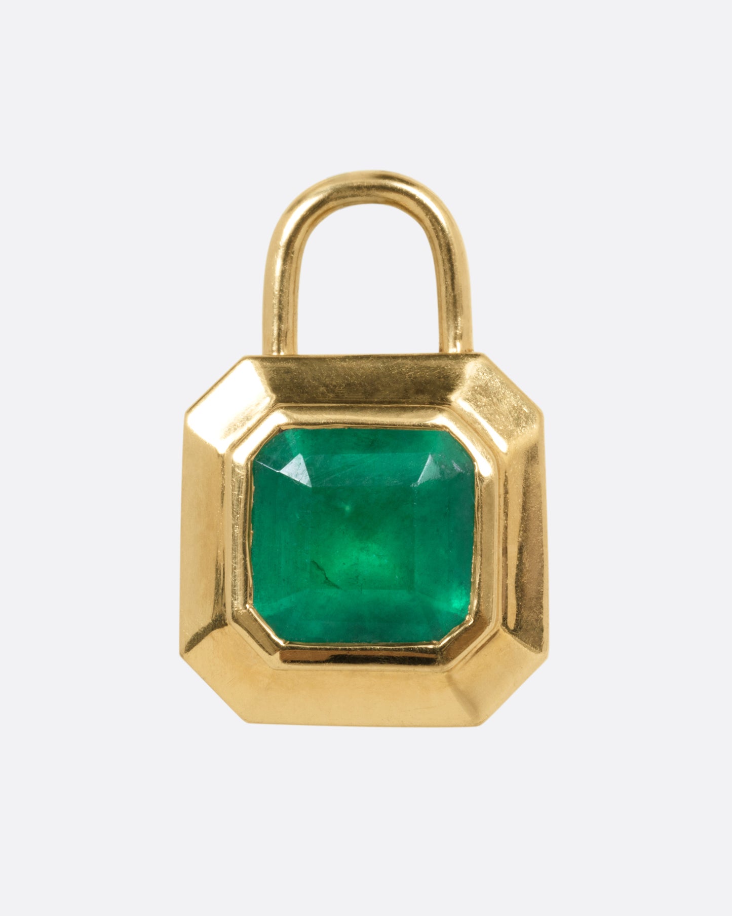 A yellow gold padlocket pendant featuring a large, faceted green emerald, shown from the front.